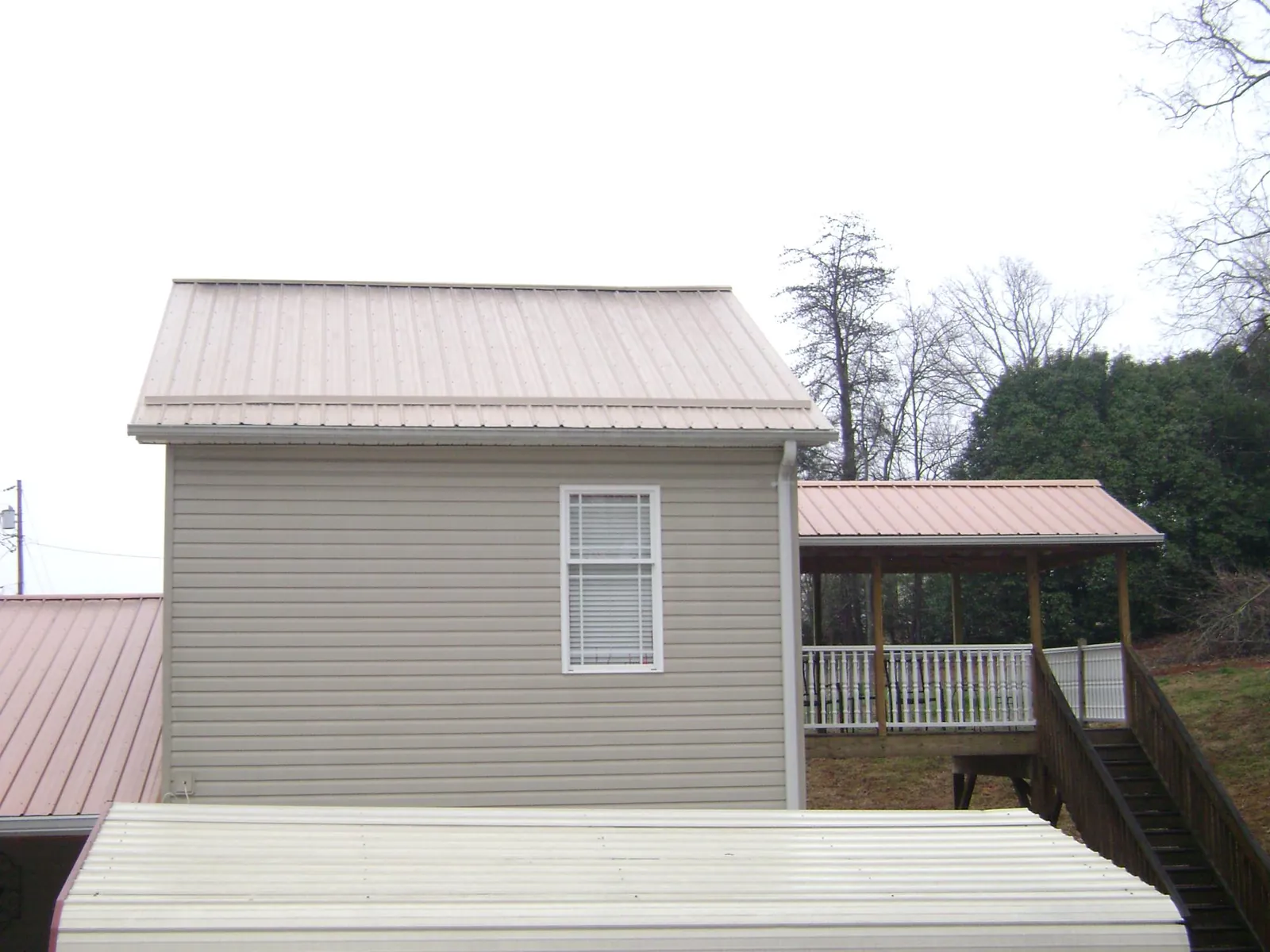 Tan metal roofs on a two story addition and attached porch, from a Roof Replacement job in Gilbert